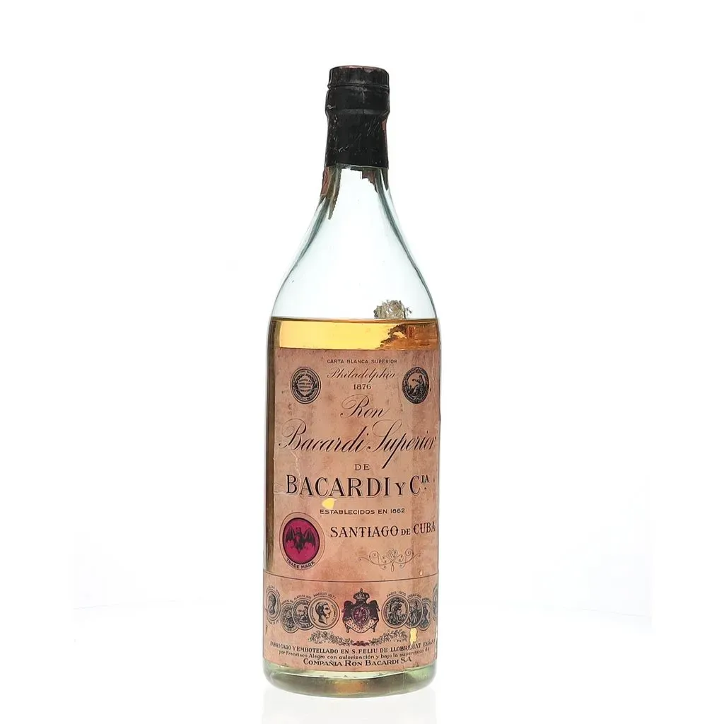 A circa 1940s bottling of Bacardi Carta Blanca Superior distilled by the Bacardi family at their Santiago de Cuba distilleries. The brand was founded in 1862 by Facundo Bacardi Masso, a Catalonian merchant who opened two distilleries to create both a light and heavy style of rum. His blended rum was a huge hit and allowed Facundo to purchase more and more distilleries, expanding further into Mexico and Puerto Rico. The Bacardi family held the firm until the company was seized by Fidel Castro in 1959 amid the Cuban Revolution. As the nation began nationalising industry, Bacardi moved its headquarters and continued production in Puerto Rico, Brazil, Spain, Canada and Mexico. This was bottled in Spain under the supervision of the Bacardi family who opened bottling facilities there in 1910. The tax stamp affixed to this bottle suggests this is likely a liter sized bottling, whilst BAXUS cannot be 100% certain of this the physical size of the bottle indicates this to be accurate.