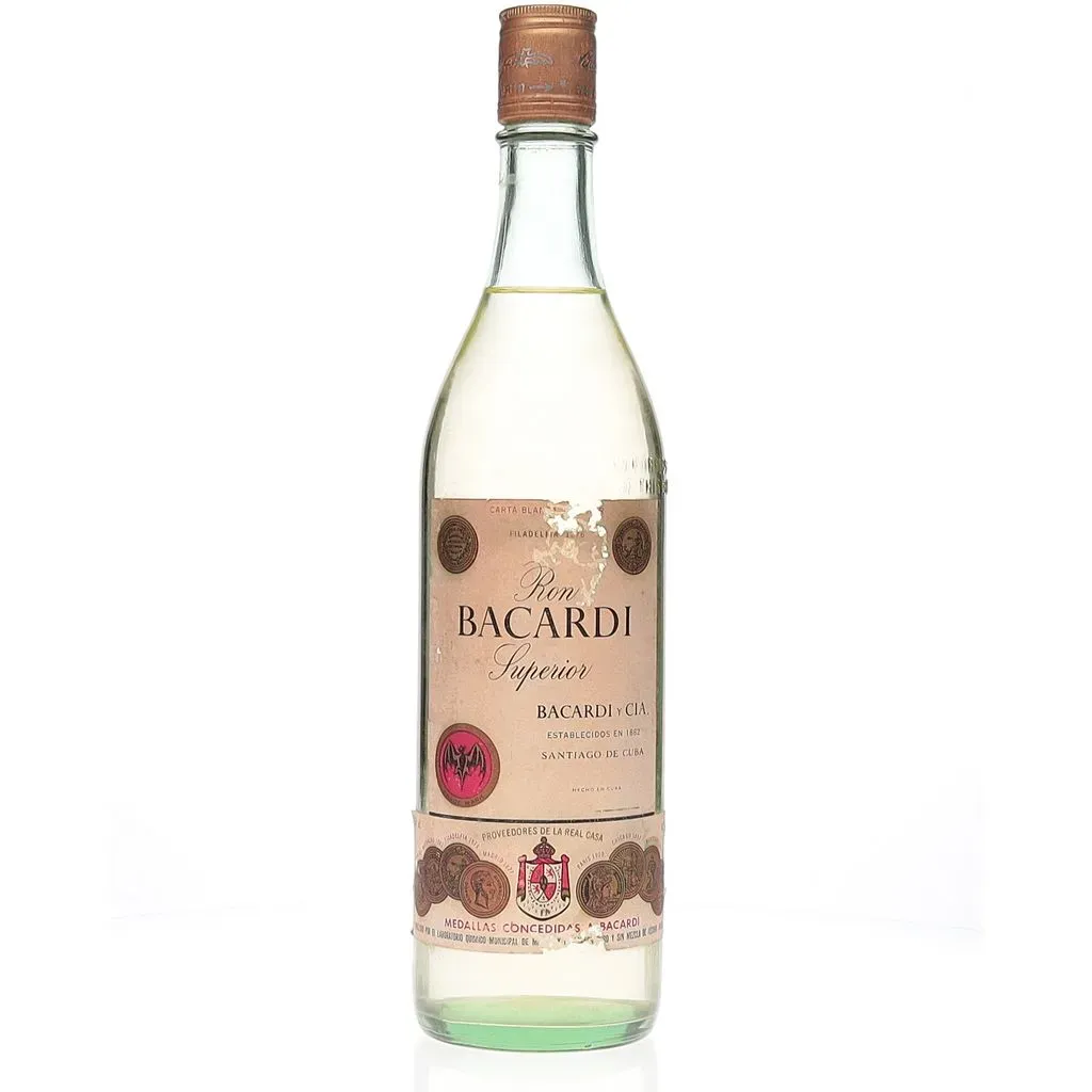 A 1960s era vintage of Bacardi Carta Blanca Superior distilled at their Santiago de Cuba distilleries. The brand was founded in 1862 by Facundo Bacardi Masso, a Catalonian merchant who opened two distilleries to create both a light and heavy style of rum. His blended rum was a huge hit and allowed Facundo to purchase more and more distilleries, expanding further into Mexico and Puerto Rico. The Bacardi family held the firm until the company was seized by Fidel Castro in 1959 amid the Cuban Revolution. As the nation began nationalising industry, Bacardi moved its headquarters and continued production in Puerto Rico, Brazil, Spain, Canada and Mexico.